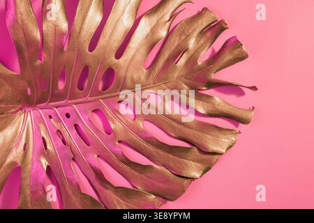 Golden tropical di foglie di palma Monstera sul pastello rosa di lusso . Configurazione astratta per la progettazione e lo spazio per il testo. Foto Stock