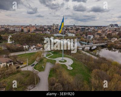 Foto aerea di una gigantesca bandiera Ucraina che sventola sopra lo skyline della città di Vinnytsia. La bandiera nazionale blu e gialla domina la cornice con il bac urbano Foto Stock