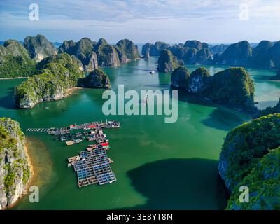 Veduta aerea dell'arcipelago Cat Ba con carsiche calcaree, allevamenti ittici galleggianti e barche sulle acque turchesi di ha tu, hai Phong, Vietnam. Foto Stock