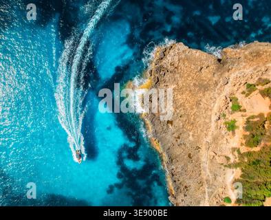 Vista aerea del motoscafo che fa onde vicino alla costa rocciosa Foto Stock