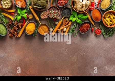 Una vibrante collezione di spezie ed erbe fresche e profumate disposte in un colorato display su uno sfondo marrone, che mostra la loro bea naturale e aromatica Foto Stock