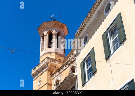 Una giornata di sole cattura l'architettura di una torre di chiesa e di un edificio a Mao, Minorca, con un cielo azzurro. Foto Stock