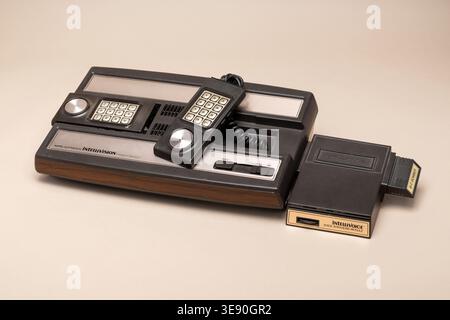 Pavia, Lombardia, Italia - 30 marzo 2026: Console Mattel Intellivision e accessorio Intellivoice vintage che rappresentano la tecnologia di gioco rétro, 1979 Foto Stock