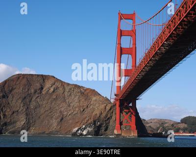 Una chiara vista del Golden Gate Bridge che si estende dalla sua base di cemento lungo le ripide scogliere rocciose dei Marin Headlands sopra San Francis Foto Stock