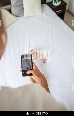 Mamma che scatta una foto di bimba di 2 mesi con lo smartphone, un blog importante Foto Stock