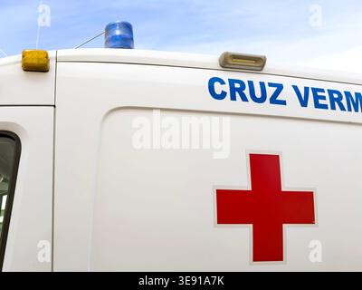 Close up view of a white Cruz Vermelha ambulance with a red cross symbol and emergency blue light against a clear sky lagos portugal Foto Stock