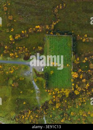 Vista aerea del cimitero di Ballesvika con file di lapidi circondati da fogliame autunnale e prati verdi a Ballesvika, Troms, Norvegia. Foto Stock