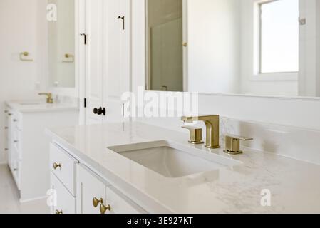 Elegante lavandino del bagno con ripiano bianco, lavabo rettangolare e finiture in tonalità oro. Foto Stock