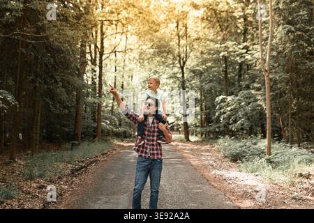Padre e figlio camminano insieme nella foresta esplorando la natura. Il genitore passa del tempo con il bambino. Papà e figlio. Buona festa del papà. Foto Stock