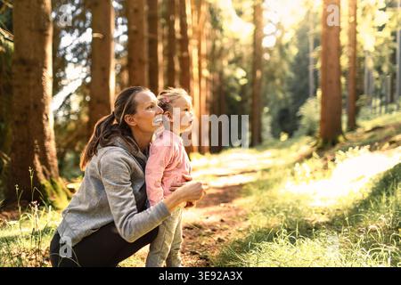 Madre figlia che si lega nella foresta autunnale, godendo la natura e la compagnia reciproca. Foto Stock