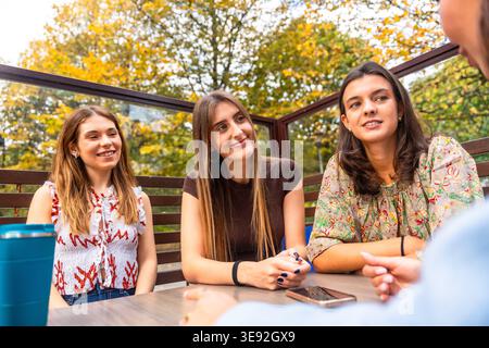 Giovani amiche che si divertono a conversare all'aperto nel patio del caffè Foto Stock