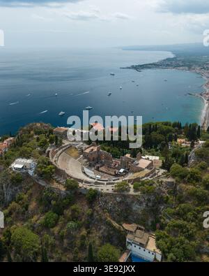 Vista aerea dell'Antico Teatro di Taormina su una scogliera rocciosa che si affaccia sul blu del Mar Ionio e sulla costa di Taormina, Sicilia, Italia. Foto Stock