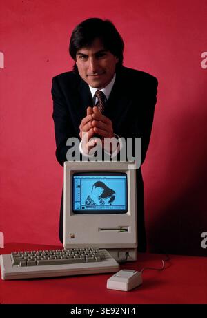 Immagine storica di Steve Jobs che si nasconde dietro un computer Apple Macintosh, mettendo in evidenza l'innovazione nel personal computing e l'ascesa della tecnologia moderna Foto Stock
