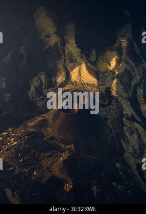 Vista aerea dei crateri vulcanici dell'Etna con campi di lava scura e depositi di zolfo sotto una luce drammatica a Castiglione di Sicilia, Sicilia, Italia. Foto Stock