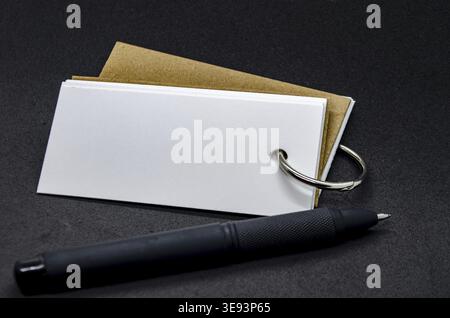 Blocco note bianco a forma di striscione con spazio personalizzabile per il testo su sfondo nero della copertina e penna nera Foto Stock