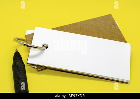 Blocco note bianco a forma di striscione con spazio personalizzabile per il testo su sfondo giallo con penna nera Foto Stock
