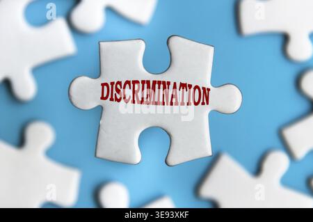 Testo discriminatorio su pezzi di puzzle isolati su sfondo blu sfocato Foto Stock