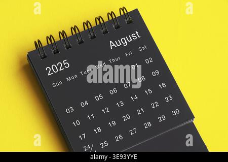 Calendario da scrivania in bianco e nero di agosto 2025 su sfondo giallo. Concetto di calendario Foto Stock