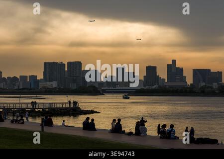 Sagome di persone ed edifici della città contro un suggestivo cielo dorato al tramonto Foto Stock