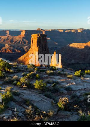 Vista aerea del Canyonlands National Park con le sue rocce rosse e le persone che si trovano sul bordo di una scogliera durante l'ora d'oro nello Utah, Stati Uniti. Foto Stock