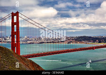 Una vista del Golden Gate Bridge mostra le barche sull'acqua e lo skyline di San Francisco sullo sfondo. Le nuvole aggiungono interesse alla scena. Foto Stock
