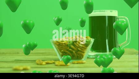 Mostra ciotola di pretzel e tazza di birra verde scuro schiumosa sul tavolo di studio in legno, cuori che fluttuano Foto Stock