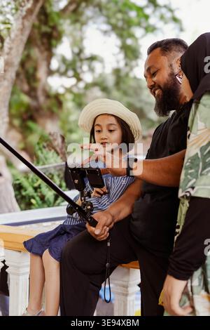 Padre e figlia barbuti che si fanno selfie all'aperto felicemente. Foto Stock