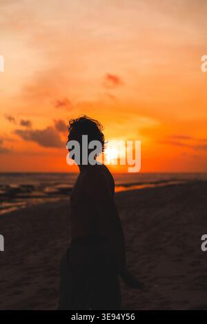 Silhouette uomo sul tramonto arancione scintillante sulla spiaggia, Nyang Nyang Foto Stock