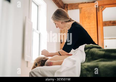 Donna che esegue un massaggio con i tessuti profondi sul cliente Foto Stock