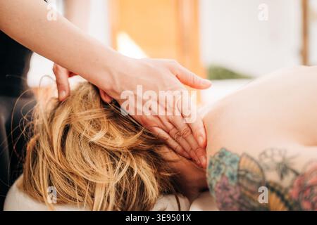Terapista che fa un massaggio rilassante al collo a una donna Foto Stock