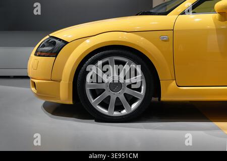 Vista laterale ravvicinata dell'Audi TT gialla nel parcheggio: Ruota anteriore, parafango, paraurti e faro. Foto Stock