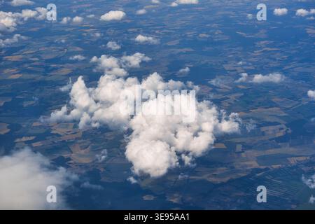 Vista aerea delle soffici nuvole bianche di cumulus sui terreni agricoli e sui campi agricoli durante il volo Foto Stock