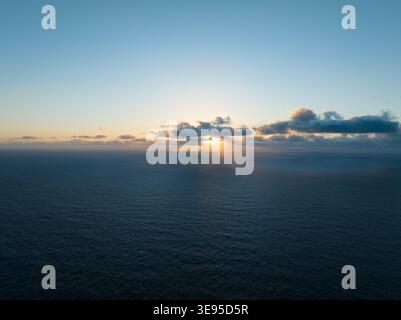 Vista aerea delle onde del sole che si infrangono attraverso le nuvole sul vasto Oceano Atlantico durante il tramonto da Miradouro do Ponta da Ladeira a Porto Moniz, Madeira, Foto Stock