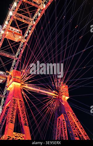 Torri di supporto della ruota panoramica e cavi illuminati di notte con gondole visibili contro il cielo scuro al parco divertimenti Foto Stock