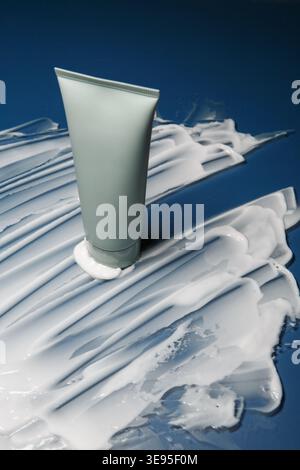 Provetta per la cura della pelle su sfondo blu con striscio di crema Foto Stock
