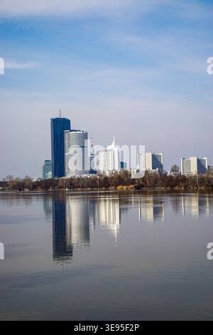 Il moderno skyline della città si riflette sulle calme acque del fiume sotto il cielo limpido e presenta alti edifici e un paesaggio urbano sul lungomare. Foto Stock
