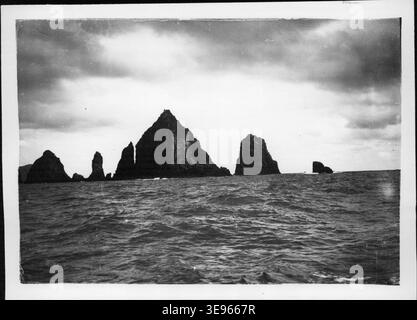 Henry Winkelmann (date sconosciute) scattò una fotografia degli aghi sulla Great Barrier Island, nuova Zelanda, nel 1908. L'immagine mostra le drammatiche caratteristiche costiere del litorale dell'isola, con formazioni rocciose appuntite e simili ad aghi sullo sfondo dell'oceano. Foto Stock