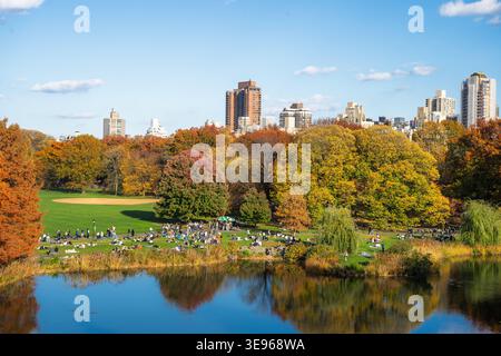 Manhattan, Stati Uniti - 8 novembre 2025: Vista del vivace fogliame di Central Park che si riflette nel tranquillo lago, un arazzo di sfumature autunnali contras Foto Stock