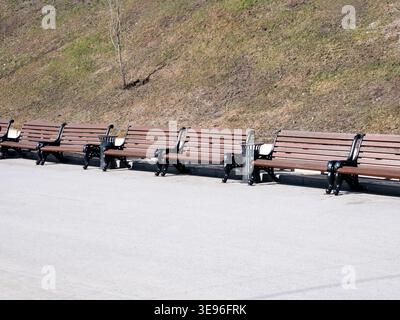 Fila di panchine del parco lungo il vicolo alberato nel paesaggio del parco urbano spazio pubblico area ricreativa tranquillo paesaggio all'aperto Foto Stock