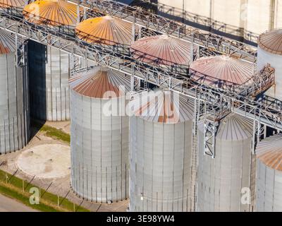 La vista aerea mostra grandi silos di grano metallico e unità di stoccaggio in aree rurali utilizzate per colture come frumento e mais durante la stagione del raccolto. Foto Stock