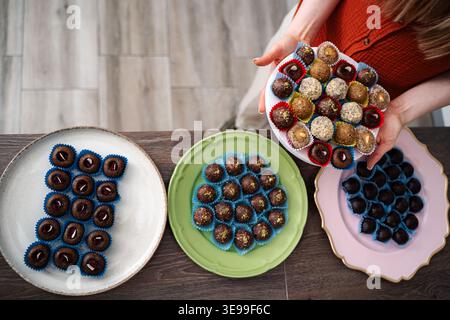Donna che tiene piatto con varie palle di energia sana e tartufi Foto Stock