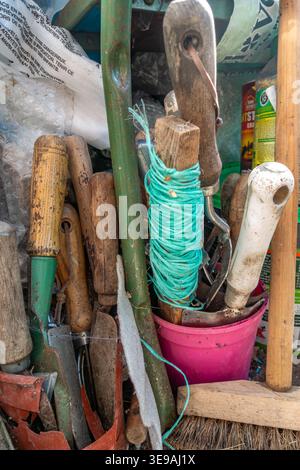 Attrezzi manuali da giardinaggio conservati sul pavimento in un angolo di una serra Foto Stock