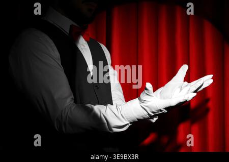 Mago che tiene qualcosa vicino alla tenda rossa Foto Stock