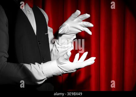 Mago che tiene qualcosa vicino alla tenda rossa Foto Stock
