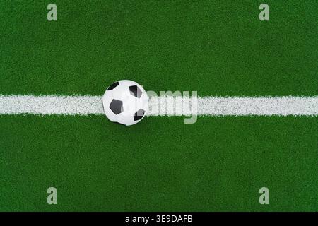 un pallone da calcio sull'erba verde in linea nello stadio di calcio. Primo piano a centrocampo con punto centrale. Foto Stock