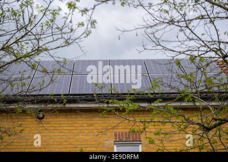 Pannelli solari sui tetti di abitazioni moderne che producono energia rinnovabile, che mostrano vita sostenibile, tecnologia verde e generazione di elettricità residenziale Foto Stock