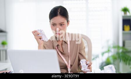 Giovane donna d'affari asiatica che si sente stressata frustrata che lavora con carta, computer portatile, moderno spazio di lavoro per ufficio Foto Stock
