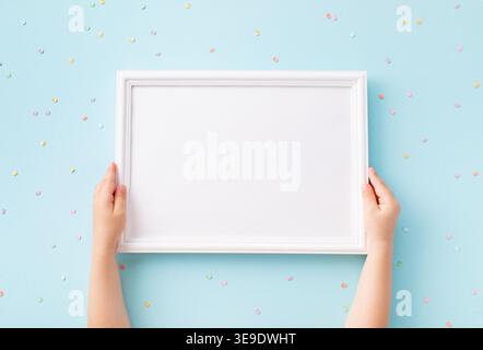 Mani per bambini con immagine vuota su sfondo blu vista dall'alto. Modello di vacanza per feste per bambini, compleanni, presentazioni o inviti. Foto Stock
