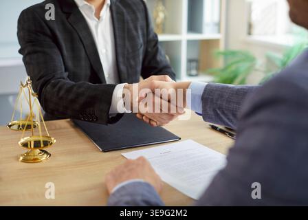 Avvocato maschio che stringe la mano con un cliente uomo seduto alla scrivania sul posto di lavoro in ufficio. Foto Stock