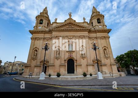 Facciata anteriore della chiesa parrocchiale di Naxxar a Malta con due campanili, statue in nicchie e un portale ad arco centrale sotto un frontone. Foto Stock